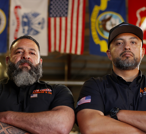 Two PDS Plumbing & Air technicians in front of the American flag