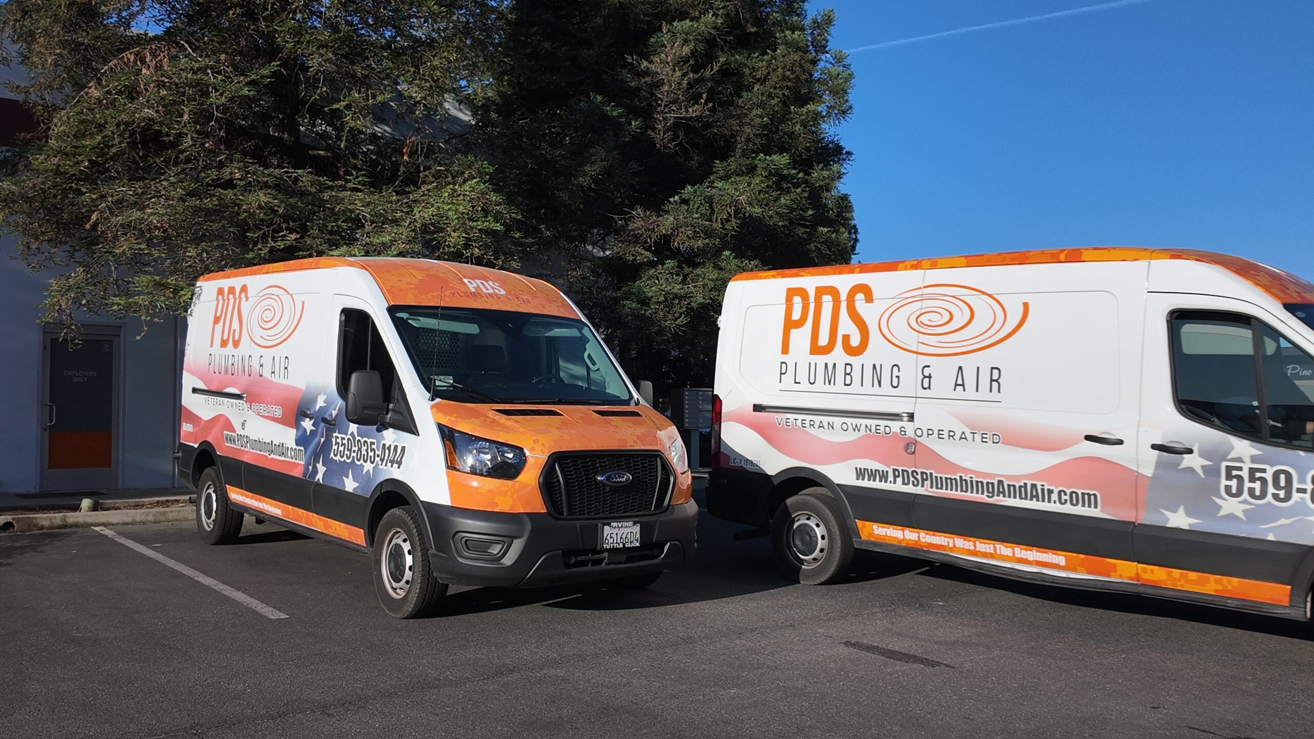 Two PDS Plumbing & Air service vans parked side by side in a Murrieta, CA parking lot, showcasing their company branding
