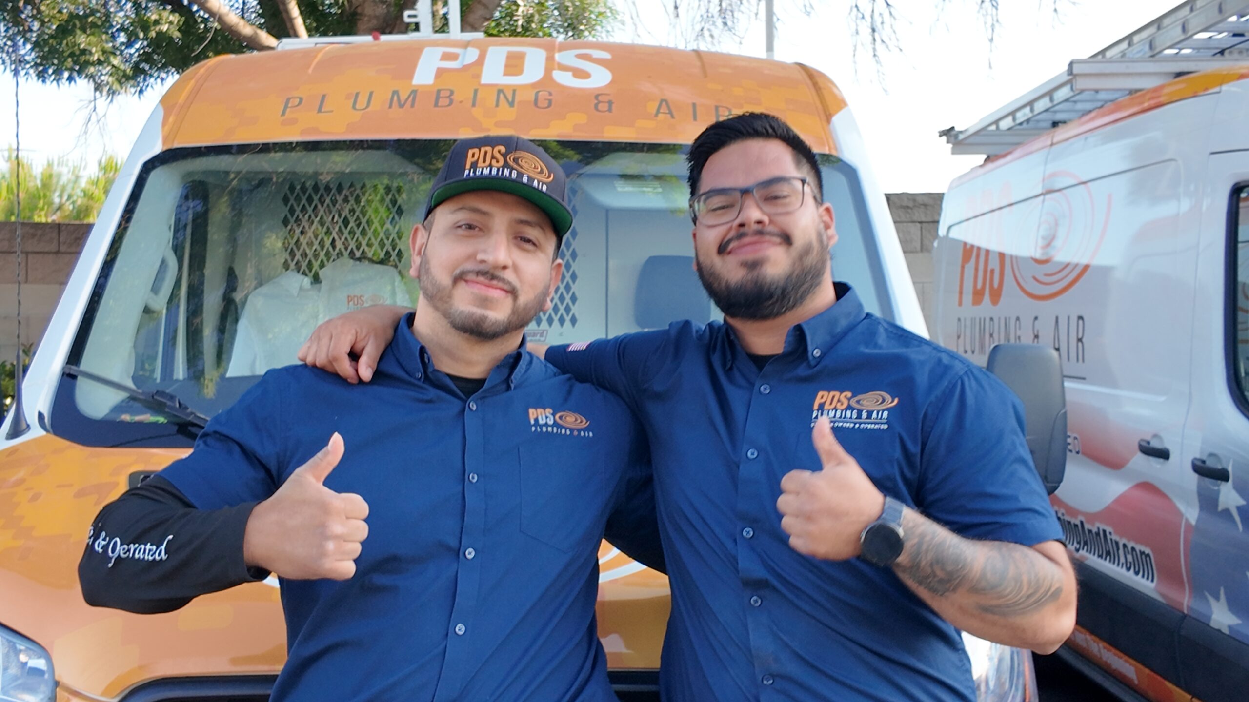 PDS technicians standing in front of company vans in Murrieta, CA, smiling and giving thumbs up—ready to provide top-notch repiping service.